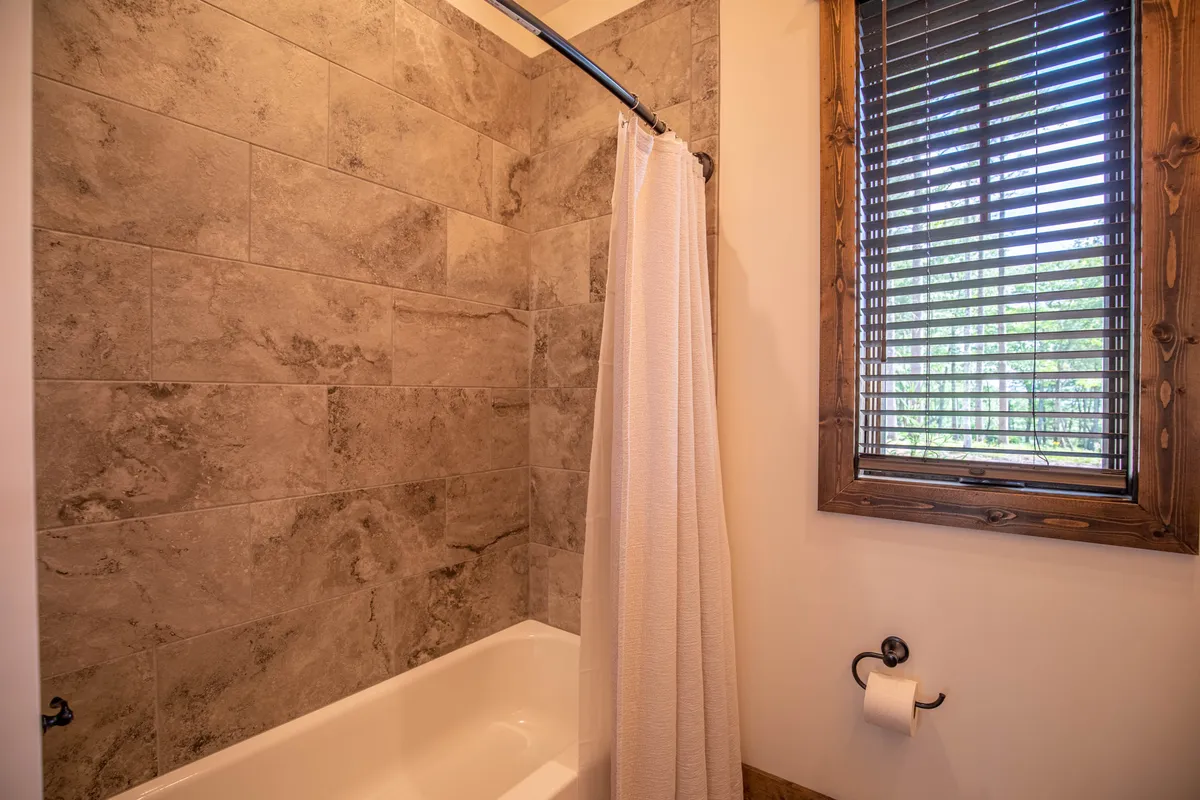 A peaceful bathroom scene with a bathtub, shower curtain, and a window letting in soft light, offering a perfect space for a soothing soak or an energizing morning shower.