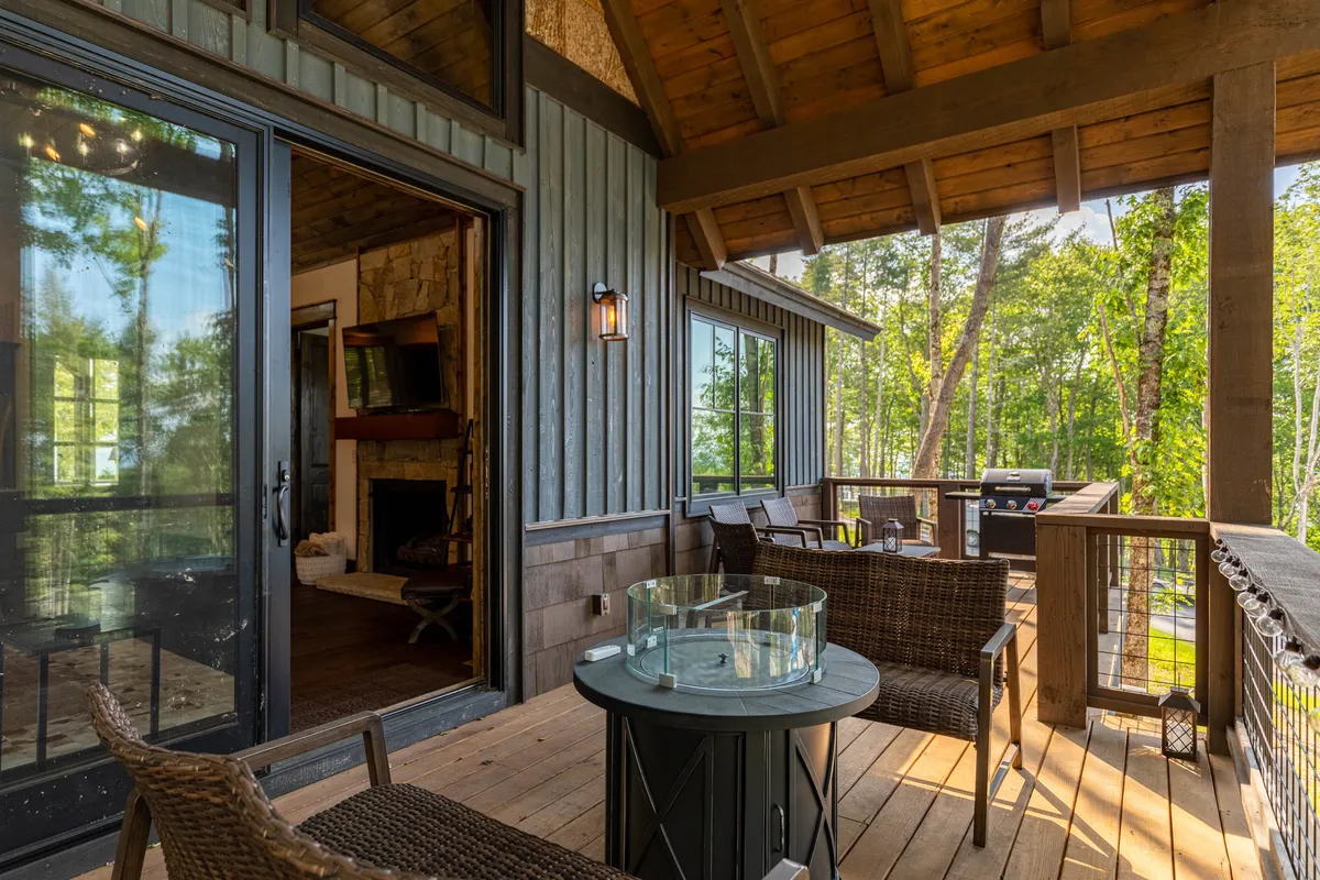 A tranquil outdoor seating area with a grill and a glass table, framed by wooden beams and surrounded by trees. The space is inviting for both relaxation and socializing, echoing the sense of retreat and outdoor enjoyment after a visit to the winery.
